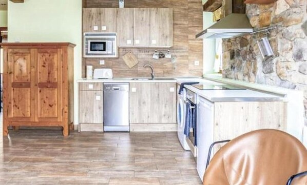 A modern kitchen with wooden cabinets, a built-in microwave, and a stone accent wall.