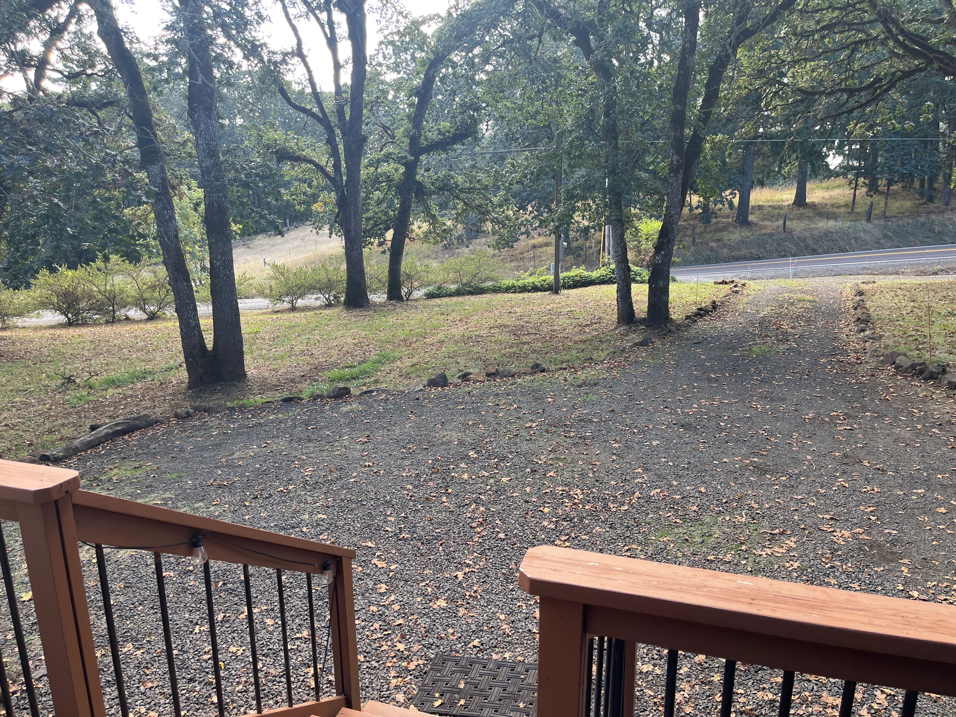 A gravel path with trees and a road in the background.