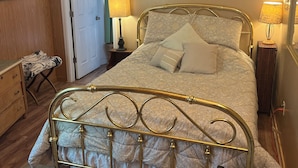 Un dormitorio con una cama con dosel, un aparador de madera, una mesita de noche con una lámpara y un cuadro enmarcado en la pared.