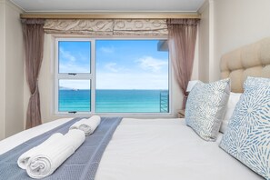 A hotel room with a bed, a view of the sea, and a balcony. - The Waves 704 - Two Bedroom Apartment, Sleeps 4 (Cape Town)