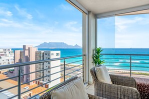 A balcony with a view of the ocean and a mountain in the distance. - The Waves 704 - Two Bedroom Apartment, Sleeps 4 (Cape Town)