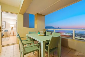 Ein Balkon mit Esstisch, Stühlen und Blick aufs Meer.