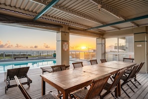 Eine Holzterrasse mit Pool, Tisch und Stühlen.