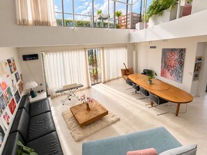 Un vaste espace de vie doté d’un haut plafond, d’une table à manger et d’un coin salon confortable.