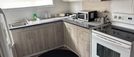 A compact kitchen with a microwave, stove, and sink.