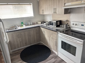 Een kleine keuken met een magnetron, fornuis en spoelbak.