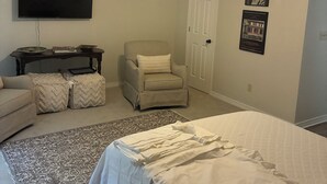 Quarto com cama, cadeira, televisão e ventilador de teto.