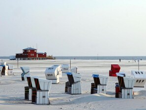 Strandkörbe mit Nummern, ein Rettungsschwimmturm und ein Sandstrand.