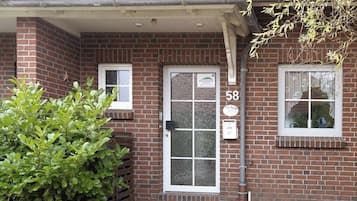 Une maison en briques avec le numéro 58 sur la porte, une petite fenêtre et une porte d’entrée.