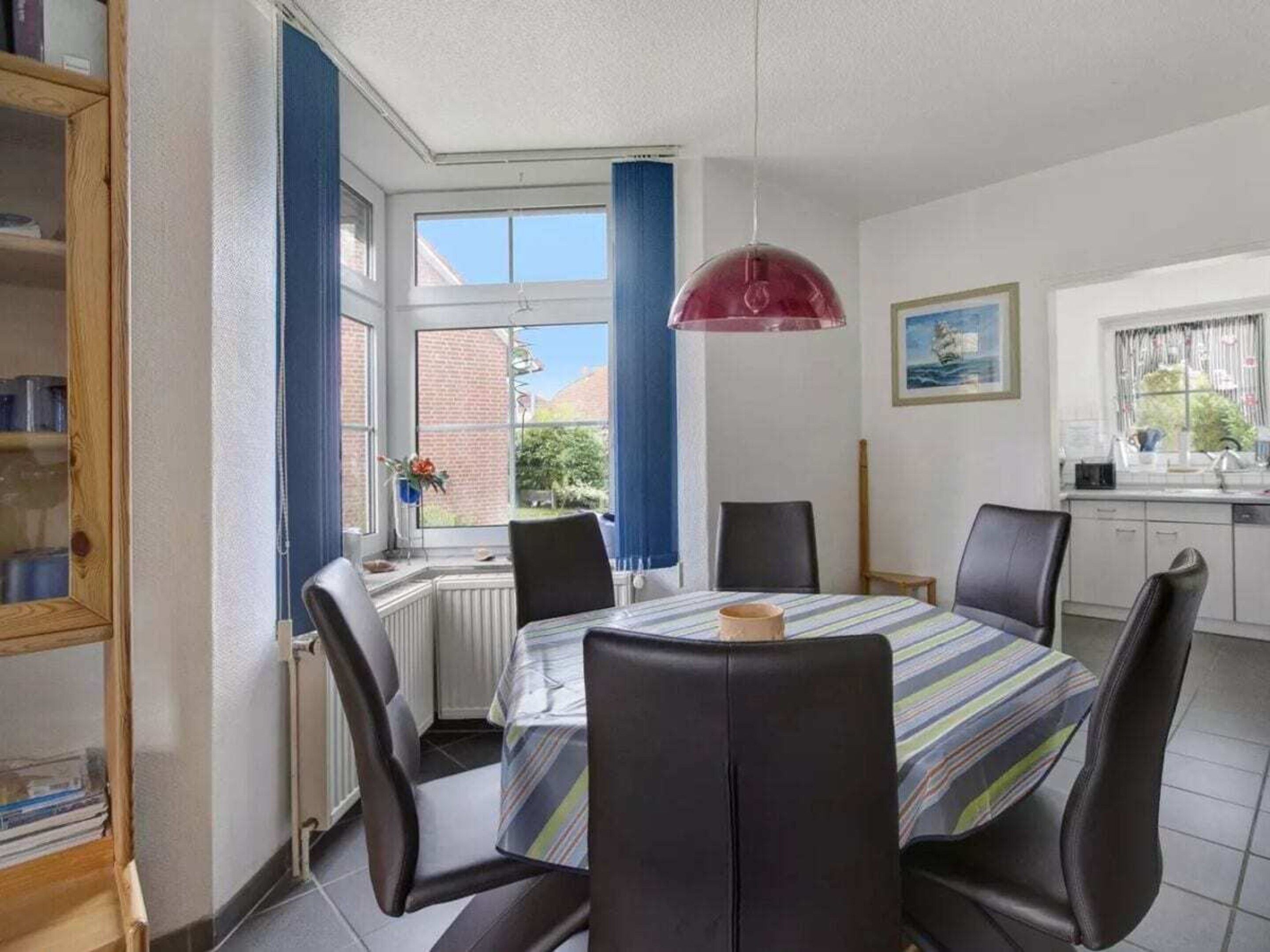 A dining area with a table, chairs, a window with curtains, and a view of the outside.