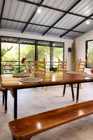 Uma sala de jantar com uma mesa de madeira comprida, várias cadeiras e um banco.