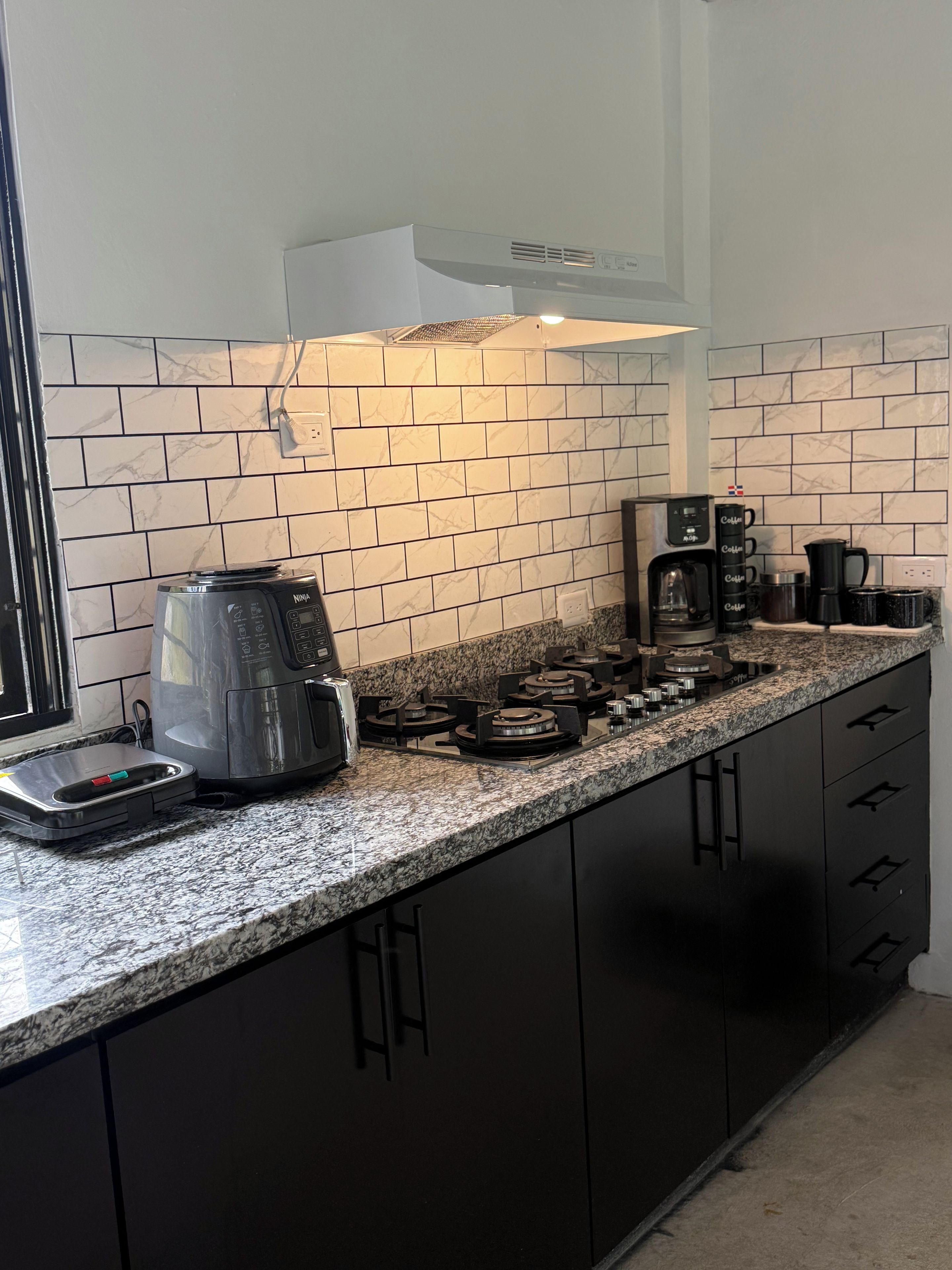 Una cocina con estufa a gas, cafetera y balanza.
