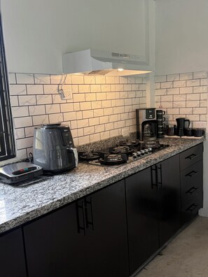 Una cocina con estufa a gas, cafetera y balanza.