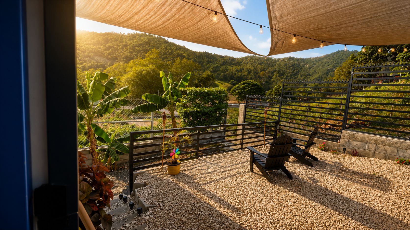 Un área de estar al aire libre con suelo de grava, cerca de madera y vista a un paisaje montañoso.