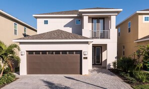 A modern two-story house with a garage, a balcony, and a well-maintained garden. - 5BR Encore Villa Movie-themed Game Room (Kissimmee)