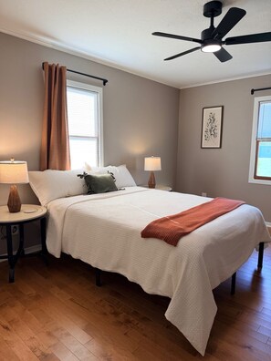 A bedroom with a bed, two bedside tables, a ceiling fan, and a window with curtains. - Newly Renovated 2BR Retreat – Minutes from CVG & Cincinnati (Petersburg)