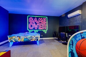 A room with a neon sign reading 'GAME OVER' on the wall, a pool table, and a basketball hoop. - 5BR Bear's Den Estate Arcade, Pool & Game Room (Kissimmee)