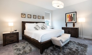 Ein Schlafzimmer mit einem großen Bett, Nachttischen, einem Sessel, einem Teppich und Bildern an den Wänden.