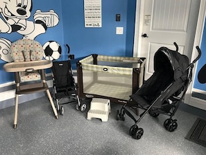 Ein Zimmer mit blauer Wand, einem Bereich zum Spielen für Kleinkinder, einem Kinderwagen und einer Tür.