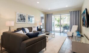 A modern living room with a sofa, coffee table, and a TV. - 6BR Encore Villa Themed Rooms & Private Pool (Kissimmee)