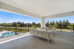 A spacious balcony with a pool, outdoor furniture, and a clear view of the surrounding area. - 5BR Bear's Den Theater, Pool & Spa (Kissimmee)