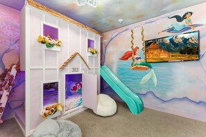 Ein Spielzimmer für Kinder mit Rutsche, Wandmalerei und einem Schild mit der Nummer 312 an einem weißen Schrank.