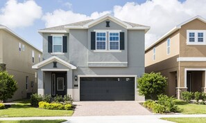 A two-story residential building with a garage, a front entrance, and a driveway. - 7BR Encore Villa With Epic Game Loft & Pool (Kissimmee)
