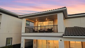 A modern two-story house with a balcony, large windows, and a tiled roof. - 5BR Bear's Den Estate Private Pool & Game Room (Kissimmee)