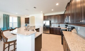 A modern kitchen with granite countertops, stainless steel appliances, and dark wooden cabinets. - 5BR Encore Villa With Billiards Loft & Pool (Kissimmee)