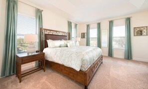 A bedroom with a wooden bed, a nightstand, a desk, and a window with curtains. - 5BR Encore Villa With Billiards Loft & Pool (Kissimmee)