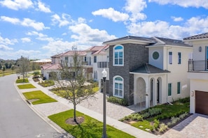 A residential area with modern houses, a clear sky, and a well-maintained lawn. - 7BR Luxe Mansion Private Pool & Golf Views (Kissimmee)