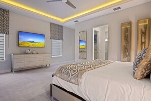 A bedroom with a bed, a dresser, a television, and a large mirror. - 7BR Luxe Mansion Private Pool & Golf Views (Kissimmee)
