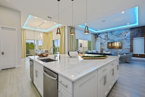 A modern kitchen with a large island, pendant lighting, and a marble backsplash. - 7BR Luxe Mansion Private Pool & Golf Views (Kissimmee)