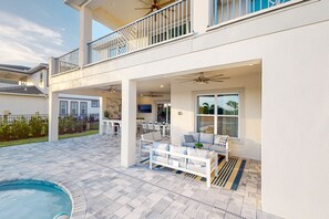 A two-story house with a covered patio area, a pool, and a dining area. - 6BR Bear's Den Estate Pool & Blacklight Arcade (Kissimmee)