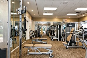 A gym with various exercise machines, mirrors, and a carpeted floor. - 6BR Bear's Den Estate Pool & Blacklight Arcade (Kissimmee)