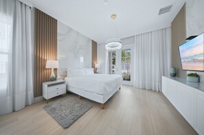 Ein modernes Schlafzimmer mit einem großen Bett, Nachttischen, einer Chandelier und einem Fernseher.