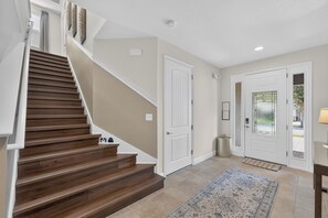 A staircase with wooden steps leading to a landing, a white door, and a patterned rug on the floor. - 6BR Encore w/ Under-the-sea Kids' Room & Pool (Kissimmee)