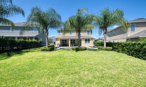 A residential area with a well-maintained lawn, a house with a front porch, and a black metal fence. - 6BR Encore Villa Pool, Spa & Game Room (Kissimmee)