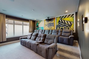 Ein Heimkinozimmer mit einer Liegesofa und einer Projektionsleinwand.