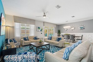 A modern living room with two sofas, a coffee table, and a dining area with chairs and a table. - 8BR Championsgate Villa Theater, Pool & Games (Davenport)
