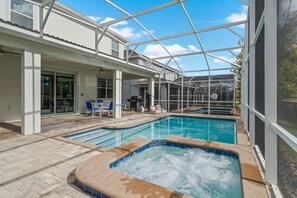 A pool area with a hot tub, lounge chairs, and a covered patio. - 8BR Championsgate Villa Theater, Pool & Games (Davenport)
