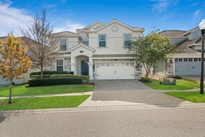A two-story residential house with a garage, a driveway, and a well-maintained lawn. - 8BR Championsgate Villa Theater, Pool & Games (Davenport)