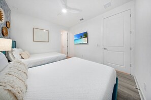 A bedroom with two beds, a ceiling fan, a beach-themed TV, and a door. - Bohemian Chic Oasis With Themed Bedrooms at Reunion (Kissimmee)