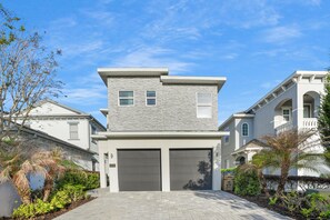 A two-story residential building with a garage, a balcony, and a well-maintained garden. - Bohemian Chic Oasis With Themed Bedrooms at Reunion (Kissimmee)