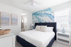Ein modernes Schlafzimmer mit einem großen Bett, einem Deckenventilator und einem Wandgemälde.