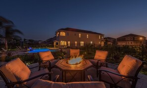 A patio with a fire feature, lounge chairs, and a swimming pool. - 5BR Encore Villa Private Pool & Fire Pit (Kissimmee)