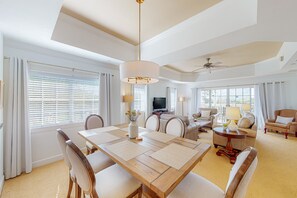 A spacious living room with a large wooden dining table, comfortable seating, and a television. - Cozy Condo With Third Floor Balcony at Reunion (Kissimmee)