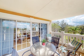 A covered outdoor area with a glass door leading to a patio, furnished with a round table, chairs, and potted plants. - Cozy Condo With Third Floor Balcony at Reunion (Kissimmee)