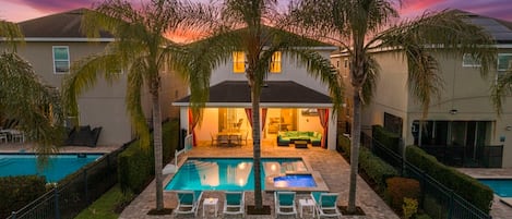 A residential property with a swimming pool, outdoor seating, and a covered patio area.