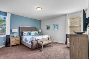 Ein Schlafzimmer mit einem Bett, Nachttischen, einer Bank, einem Schminktisch und Kunstwerken an den Wänden.